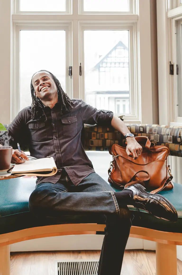 LDerick sitting on a chair and smiling while writing in a notebook